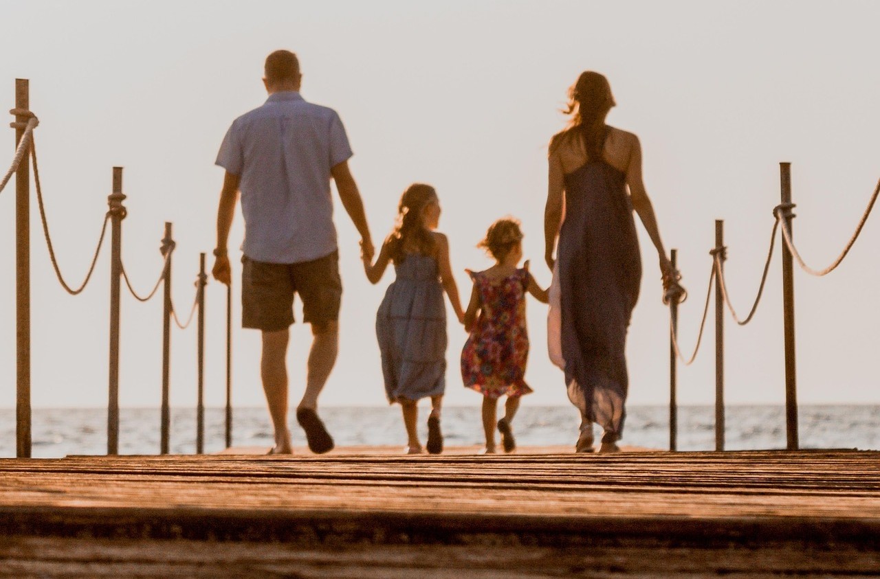 Familia perfecta caminando por un muelle hacia la plata para ilustrar artículo de psicología