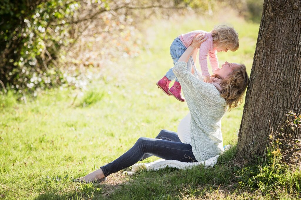 Madre con su hija en brazos, felices en el campo, para ilustrar artículo de familias perfectas