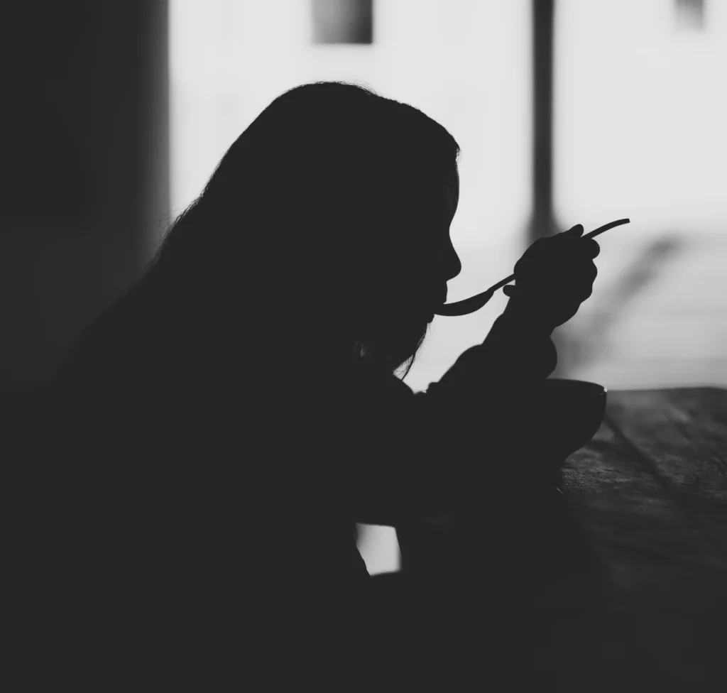 Una chica comiendo, a contraluz, para ilustrar un artículo sobre TCA