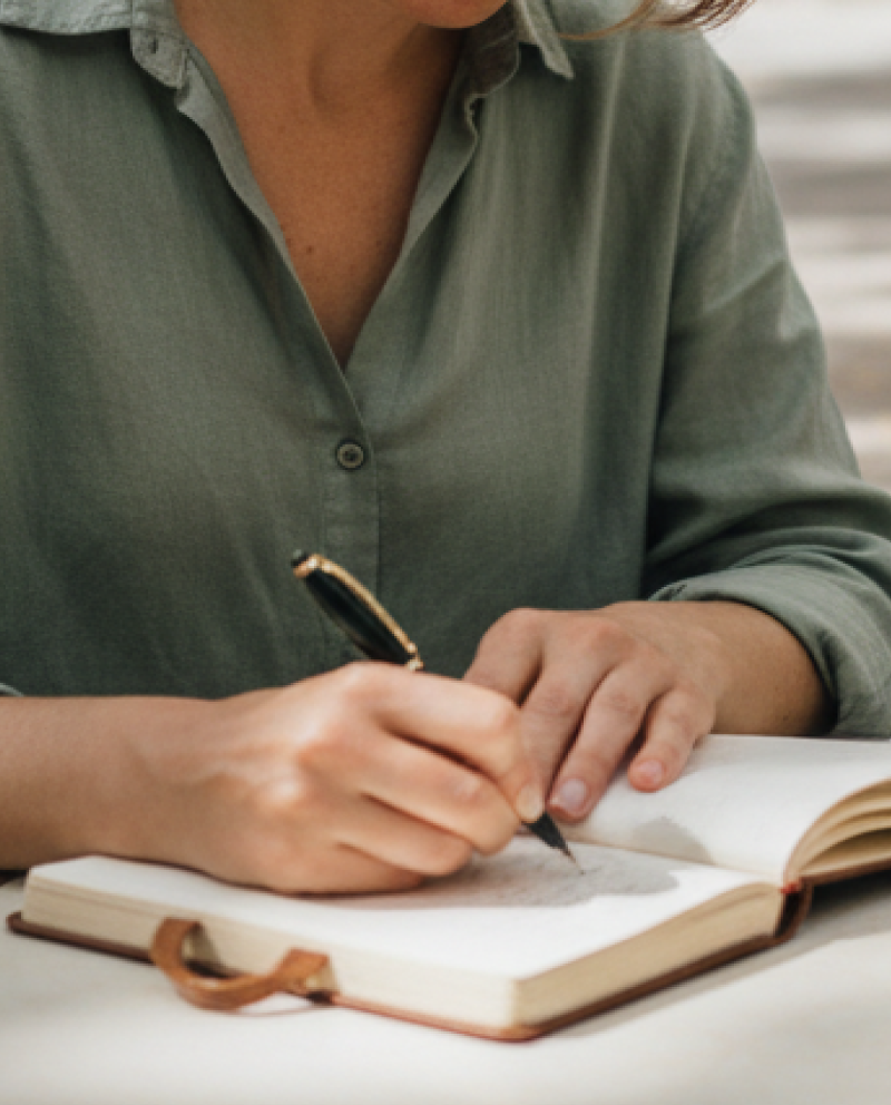 Mujer escribiendo en un cuaderno durante una sesión de terapia